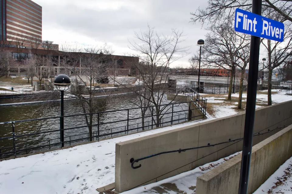 Flint River with blue sign on post in winter.